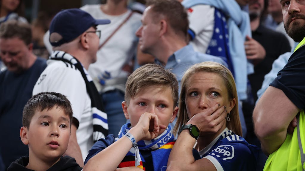 Enttäuschte HSV-Fans sitzen nach Spielende mit Tränen in den Augen in ihrem Fanblock.