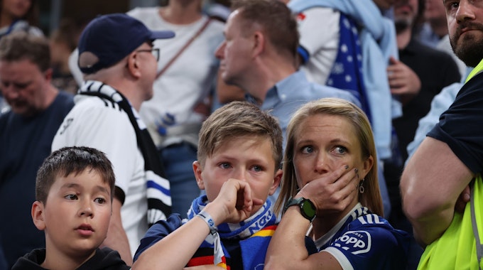 Enttäuschte HSV-Fans sitzen nach Spielende mit Tränen in den Augen in ihrem Fanblock.