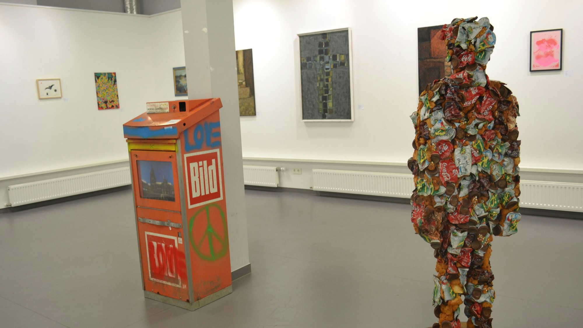 Eine Figur aus Müll steht inmitten einer Ausstellung.
