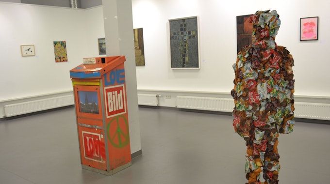 Eine Figur aus Müll steht inmitten einer Ausstellung.