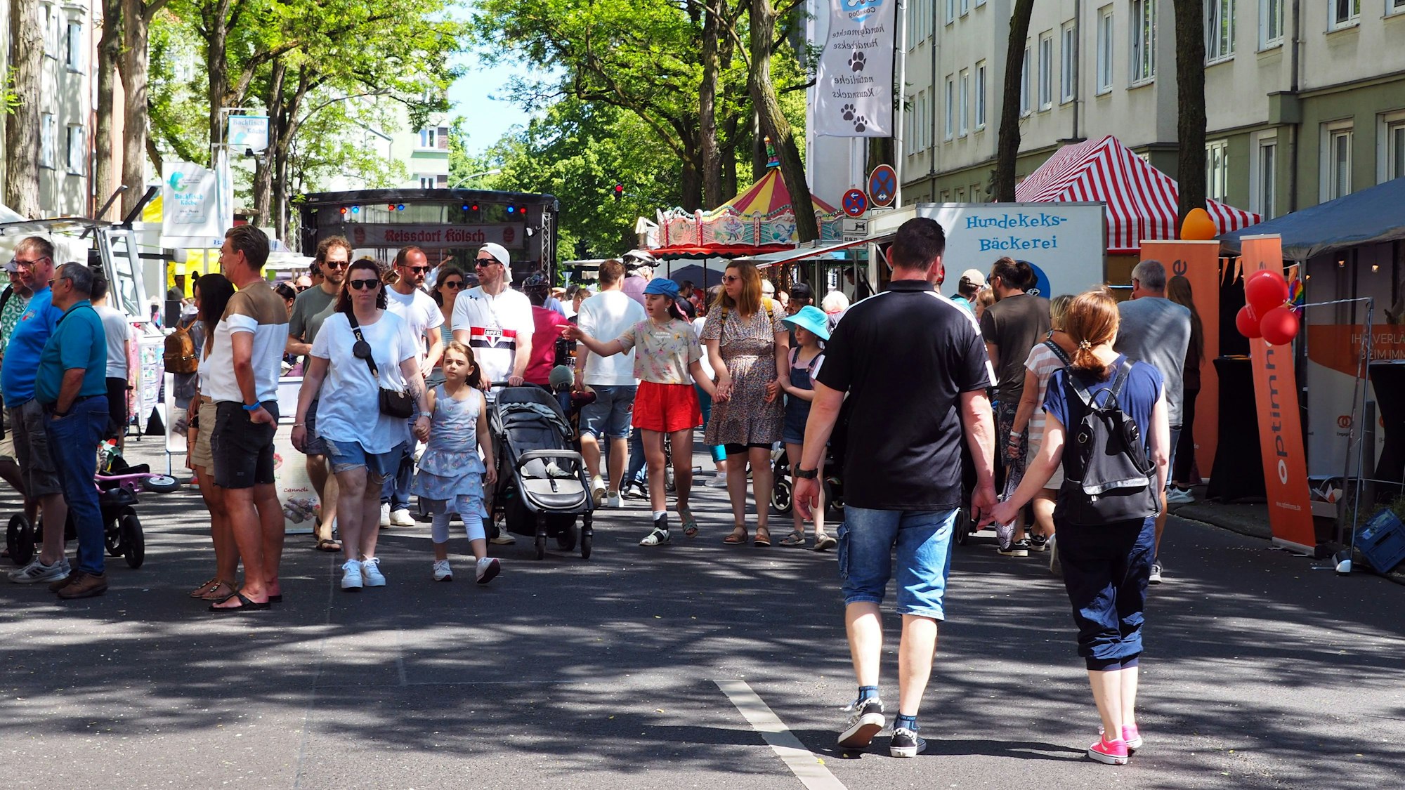 Erwachsene und Kinder laufen auf dem Frühlingsfest in Köln-Zollstock die Straße entlang.