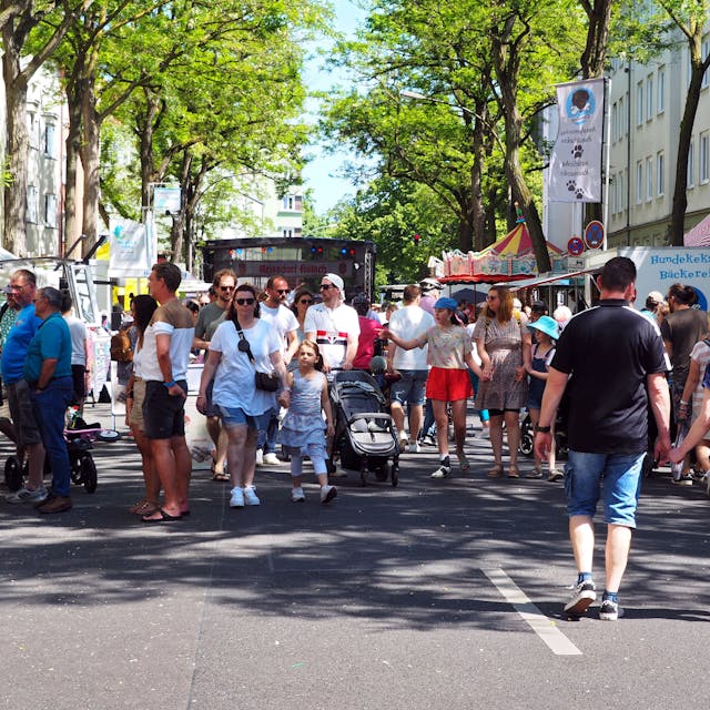Erwachsene und Kinder laufen auf dem Frühlingsfest in Köln-Zollstock die Straße entlang.&nbsp;
