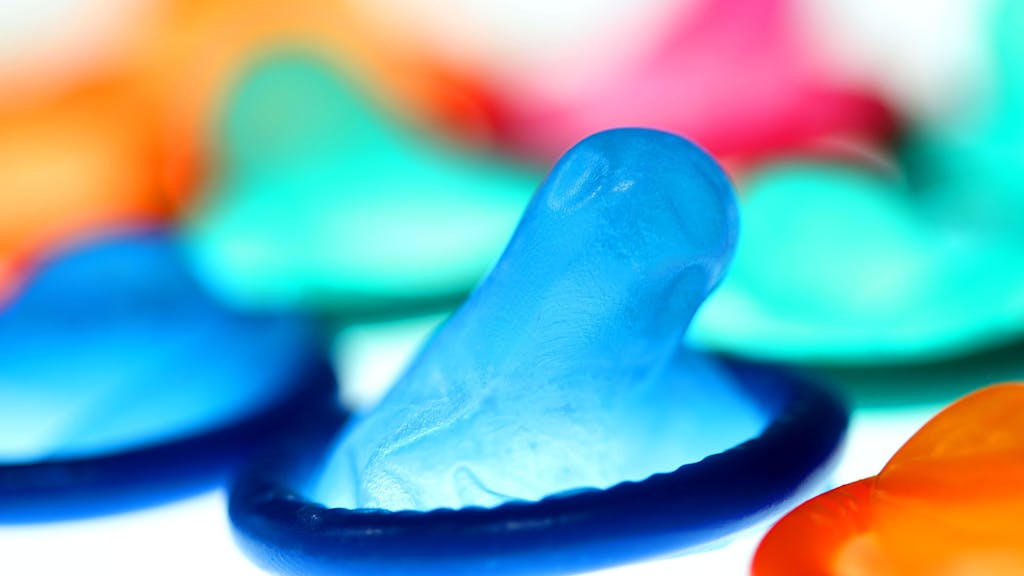 Farbige Kondome liegen auf einem Tisch.