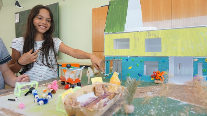 Suriya Bäcker aus der 4. Klasse der Chlodwig-Grundschule in Zülpich erklärt, wie der Außenbereich ihrer Traumschule aussehen sollte. Das macht sie mithilfe eines Modells.&nbsp;
