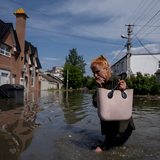 6. Juni 2023, Ukraine, Cherson: Eine Anwohnerin bahnt sich einen Weg durch eine überflutete Straße.