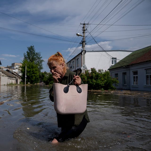 6. Juni 2023, Ukraine, Cherson: Eine Anwohnerin bahnt sich einen Weg durch eine überflutete Straße.