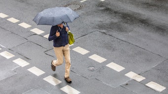20.05.2022, Köln: Ein Mann geht mit einem Regenschirm in der Hand während eines Unwetters mit Gewitter und Starkregen im Ortsteil Sülz über die Straße. Foto: Matthias Heinekamp
