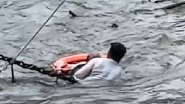 Ein Mann hält einen anderen Mann im Rhein über Wasser.