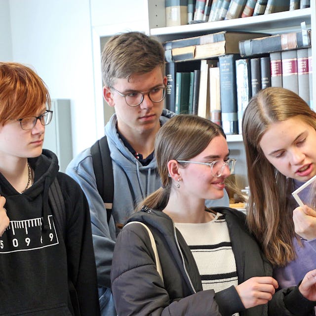 Schülerinnen und Schüler betrachten ein Papyrusfragment aus der Sammlung der Uni Köln.