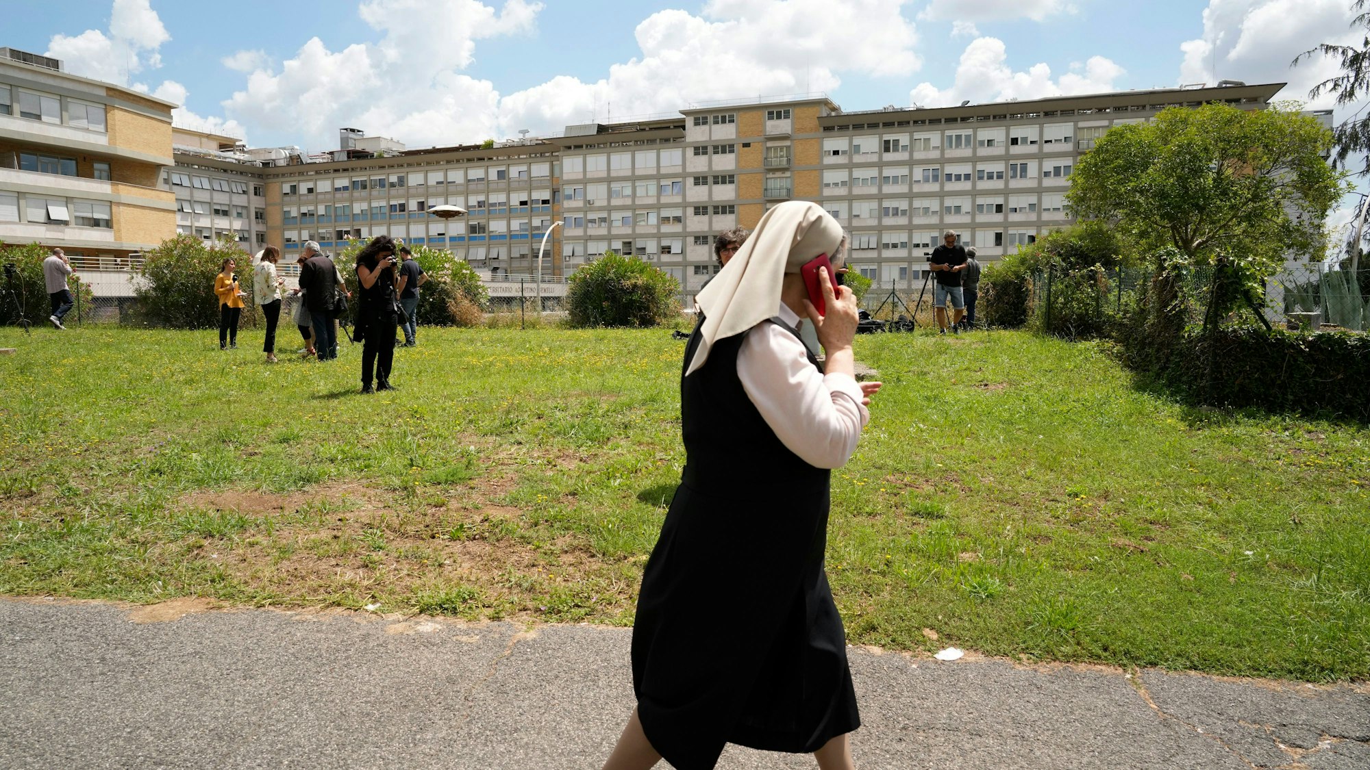 06.06.2023, Italien, Rom: Eine Nonne geht an Medienvertretern vorbei, die ihre Ausrüstung vor dem Krankenhaus Agostino Gemelli in Rom aufbauen.