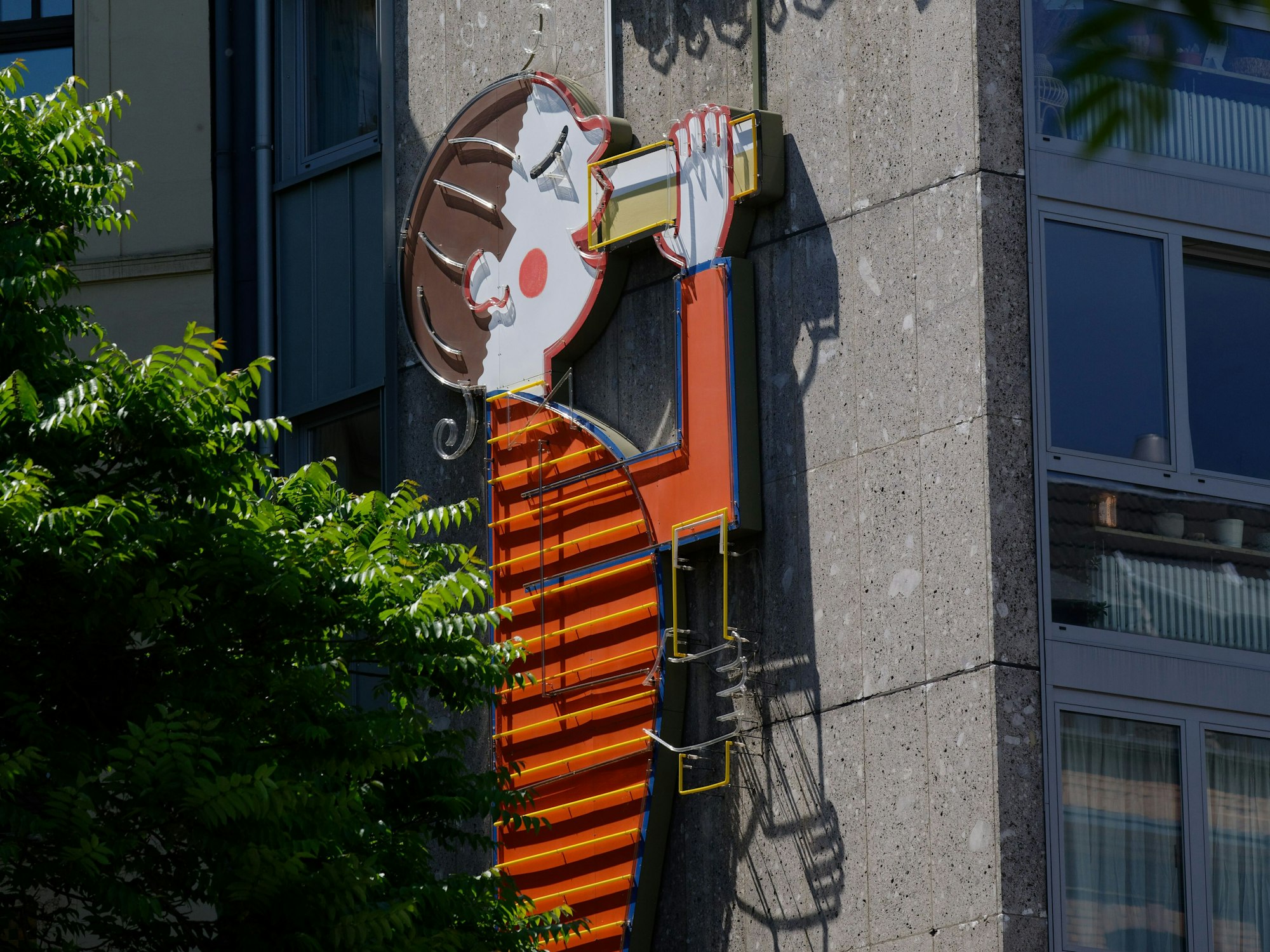 Eine Werbetafel der Kölsch-Brauerei Reissdorf an einem Haus zeigt eine Figur, die Kölsch trinkt.
