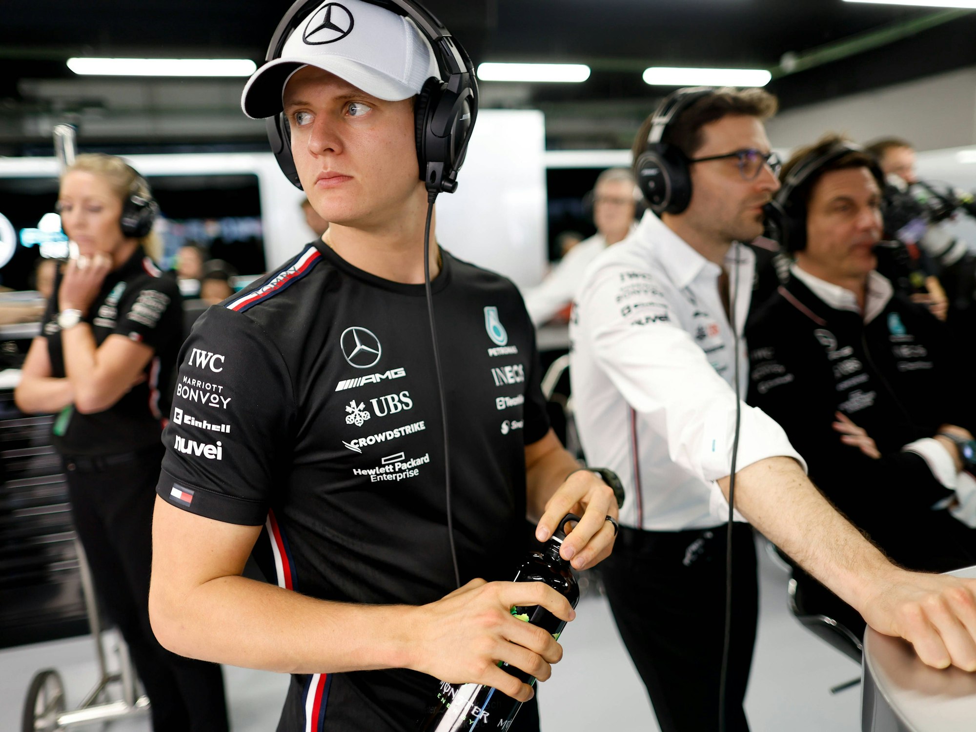 Dennis Schumacher mit Kappe und Kopfhörer in der Mercedes-Garage.