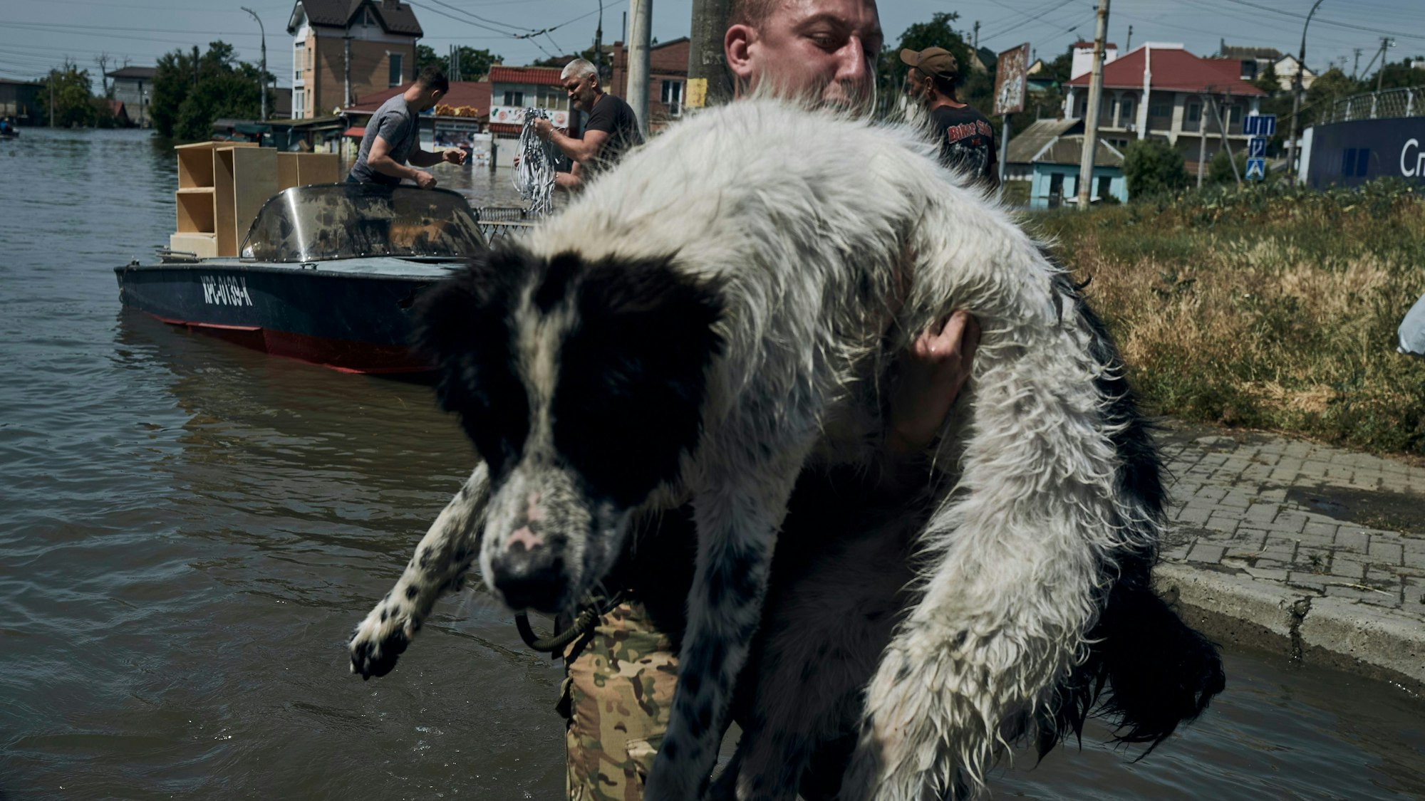 07.06.2023, Ukraine, Cherson: Ein Anwohner trägt einen nassen Hund während der Evakuierung aus einem überfluteten Stadtteil. Die Flutkatastrophe in Folge der Staudamm-Zerstörung am Dienstag hat mehr als 20 Museen und Kulturstätten der südukrainischen Region Cherson getroffen. Foto: LIBKOS/AP/dpa +++ dpa-Bildfunk +++