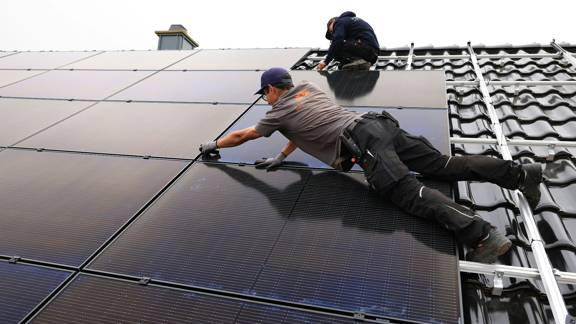 18.08.2022, Nordrhein-Westfalen, Nettersheim: Handwerker montieren auf dem Dach eines Wohnhauses Solarmodule. Foto: Oliver Berg/dpa +++ dpa-Bildfunk +++