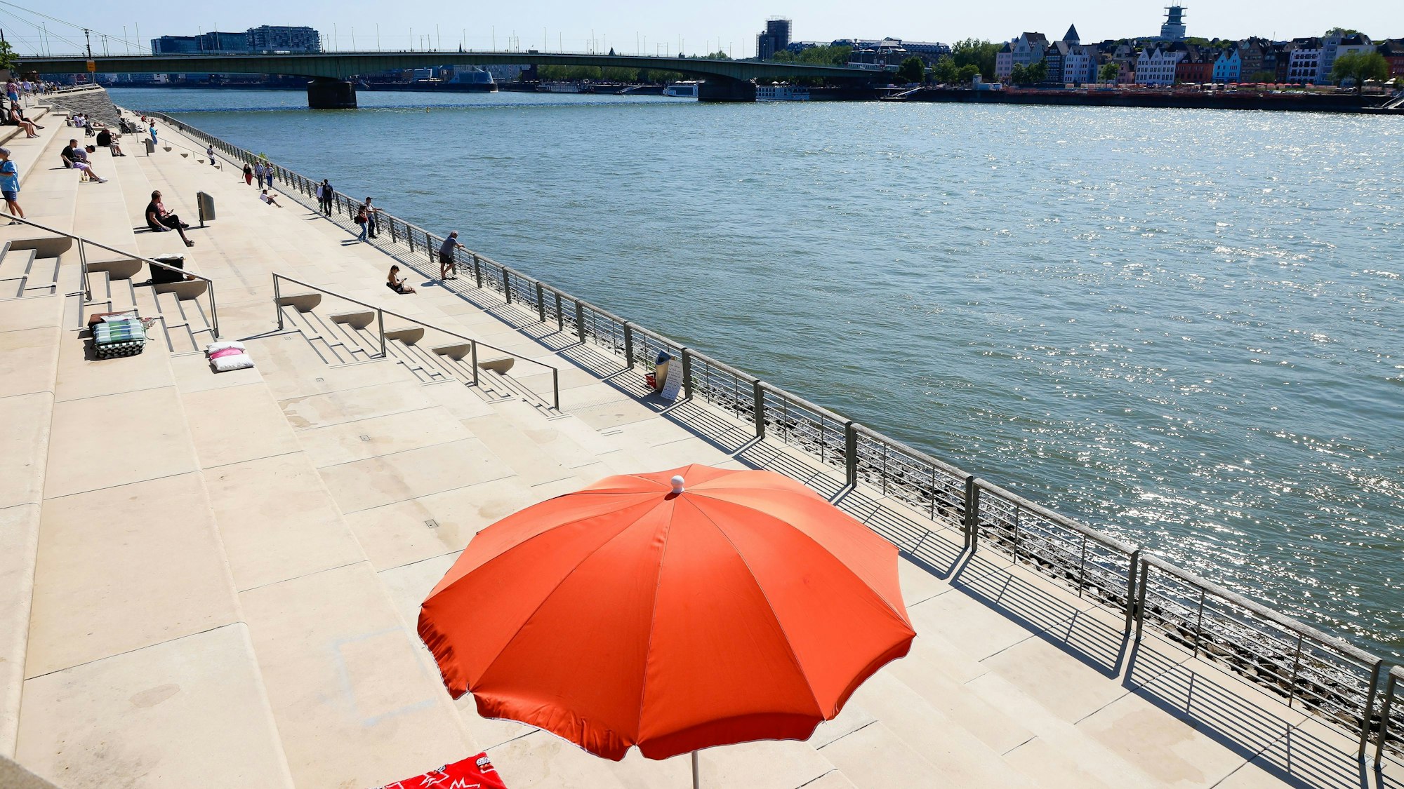 auf Treppen am Rhein steht ein roter Sonnenschirm