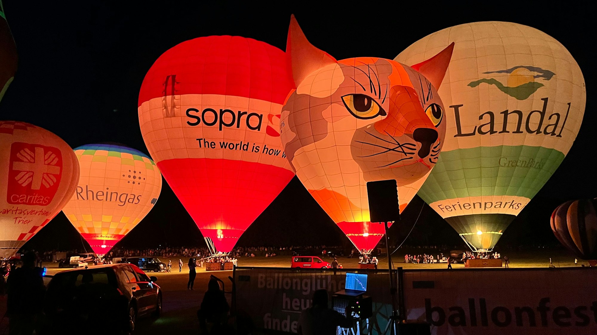 fünf leuchtende Heißluftballone stehen in der Dunkelheit nebeneinander
