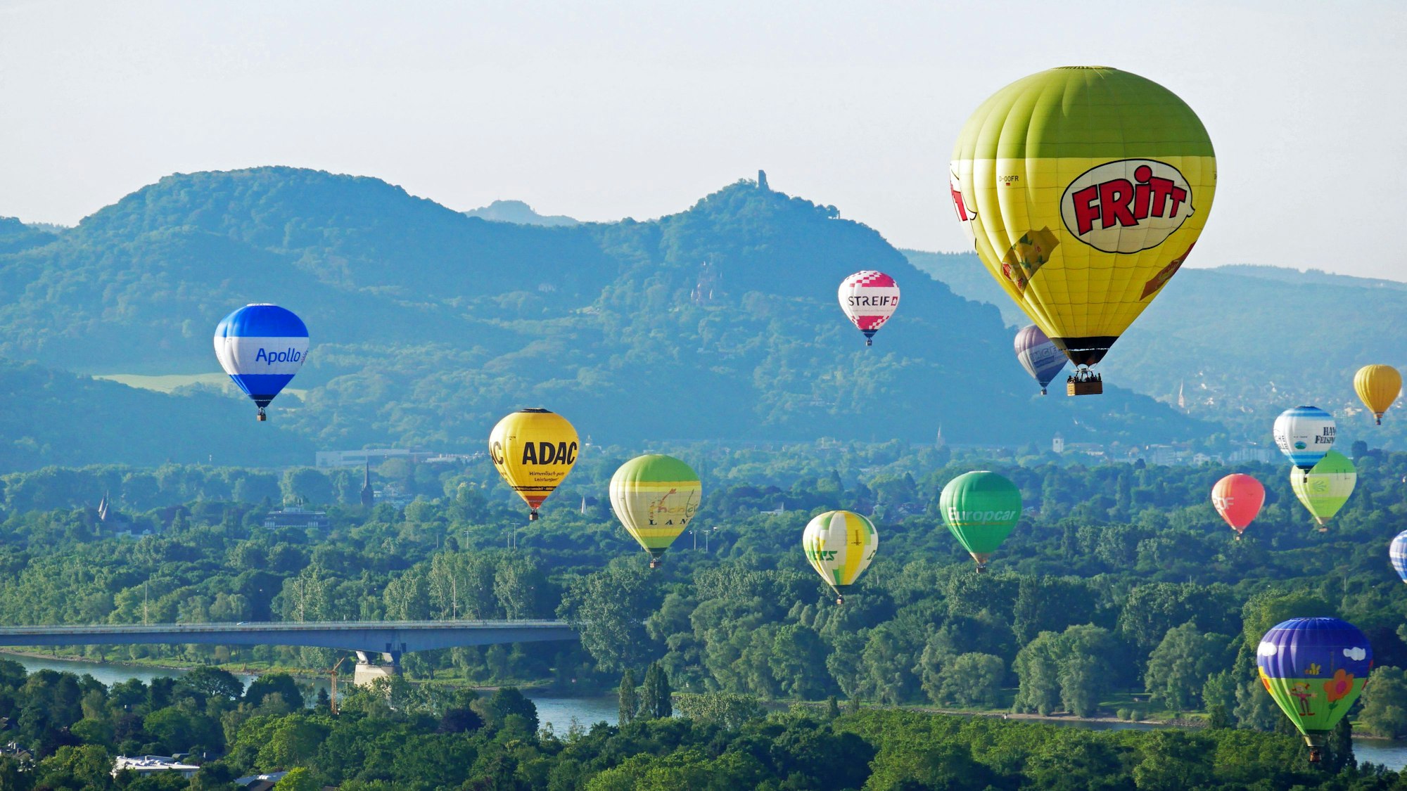 viele bunte Heißluftballone fahren über dem Rhein, Berge im Hintergrund