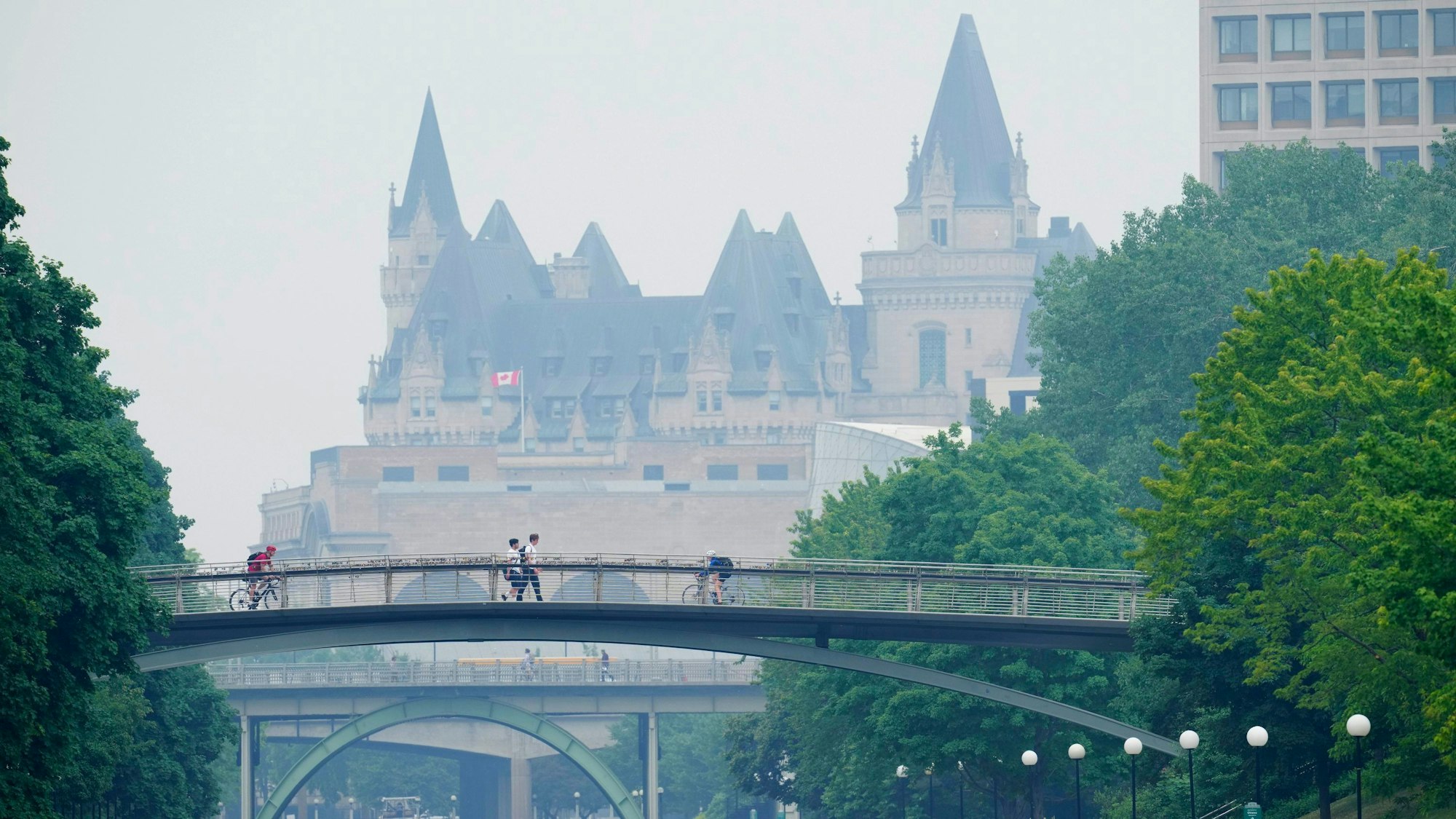 Menschen gehen über den Rideau-Kanal in Ottawa, während Rauch von Waldbränden die Luft erfüllt.