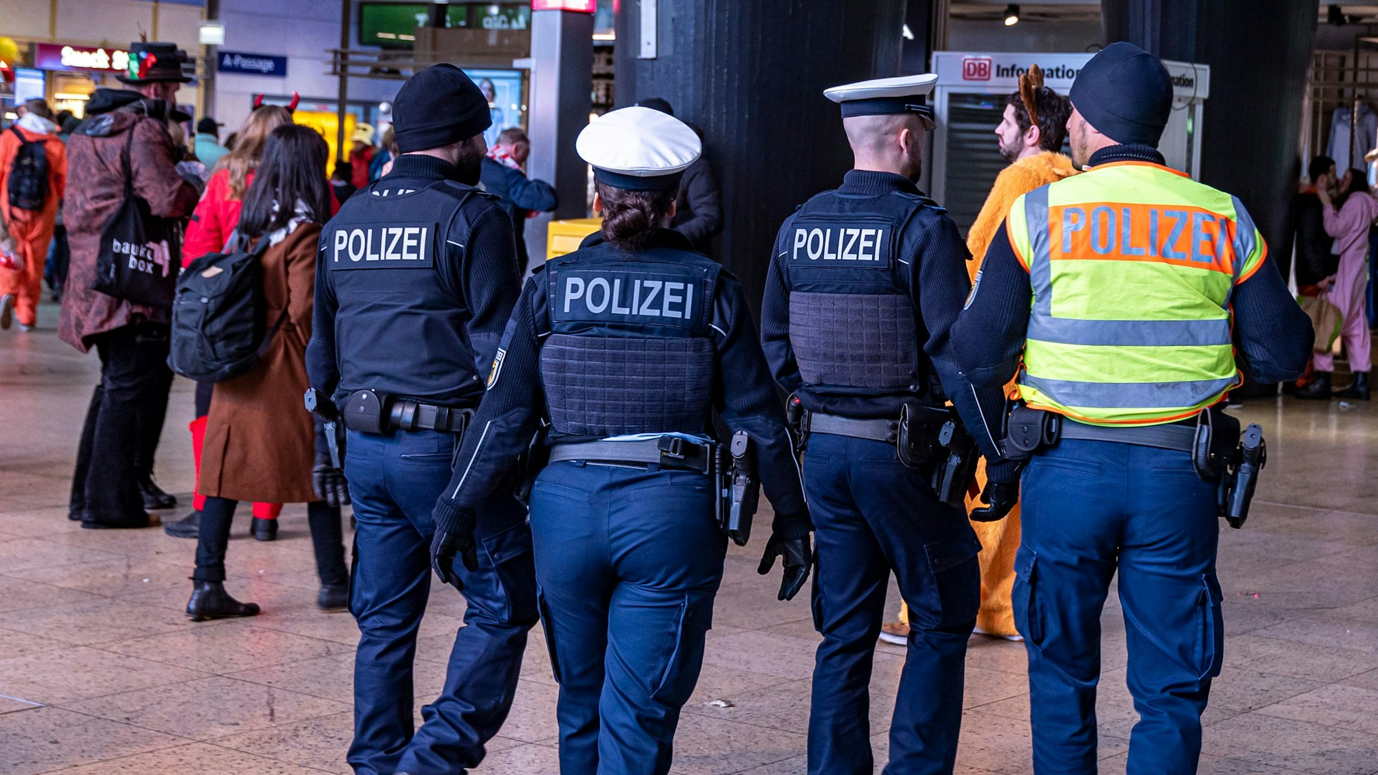 Vier Einsatzkräfte der Polizei laufen durch den Kölner Hauptbahnhof.