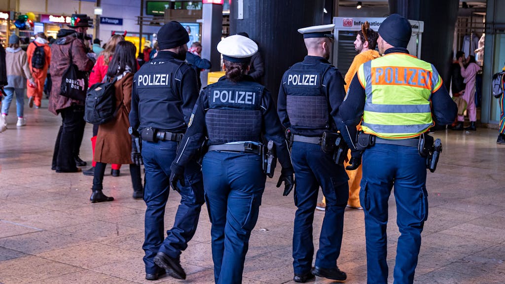 Vier Einsatzkräfte der Polizei laufen durch den Kölner Hauptbahnhof.&nbsp;