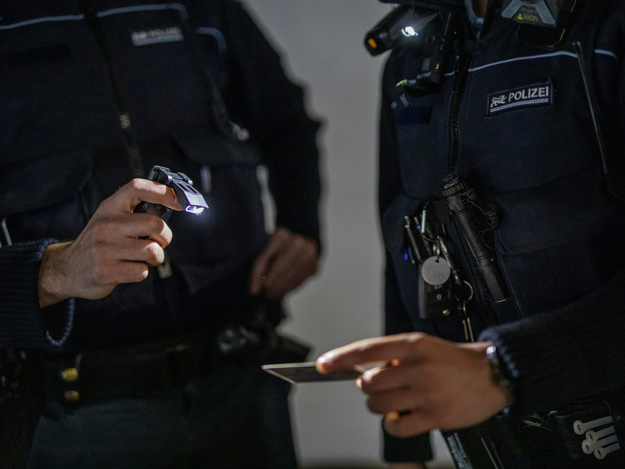 Zwei Einsatzkräfte der Polizei kontrollieren einen Personalausweis.