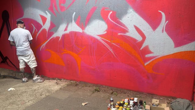 Sprayer One Take vor einer Graffiti-Wand.