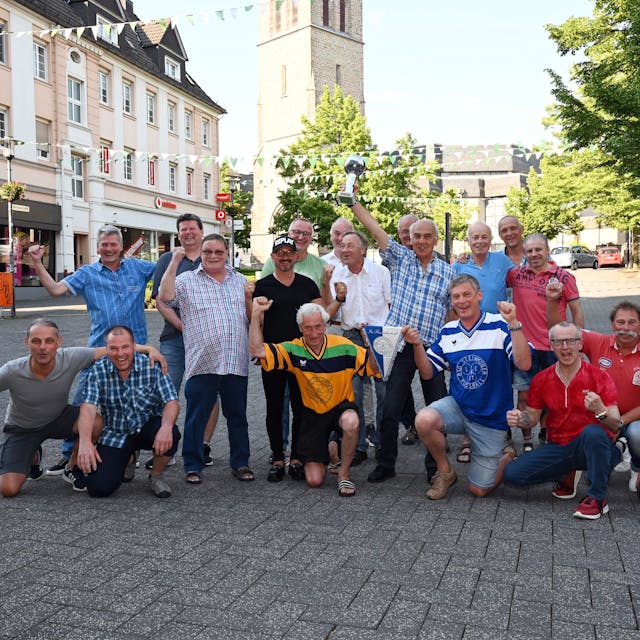 Eine Gruppe Männer posiert für ein Gruppenbild in der Gummersbacher Fußgängerzone. Einer hält einen Pokal in die Höhe.
