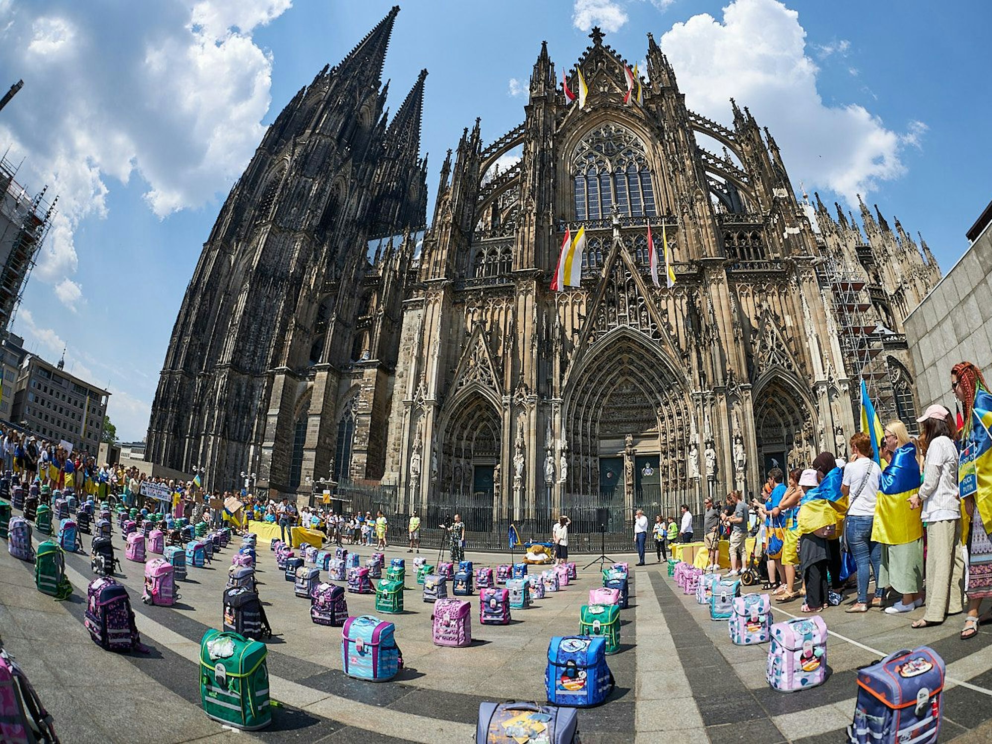 Schulranzen-Demo am Kölner Dom vom Blau-Gelben Kreuz. Die Aktion soll an die betroffenen Kinder des Ukraine-Kriegs erinnern.