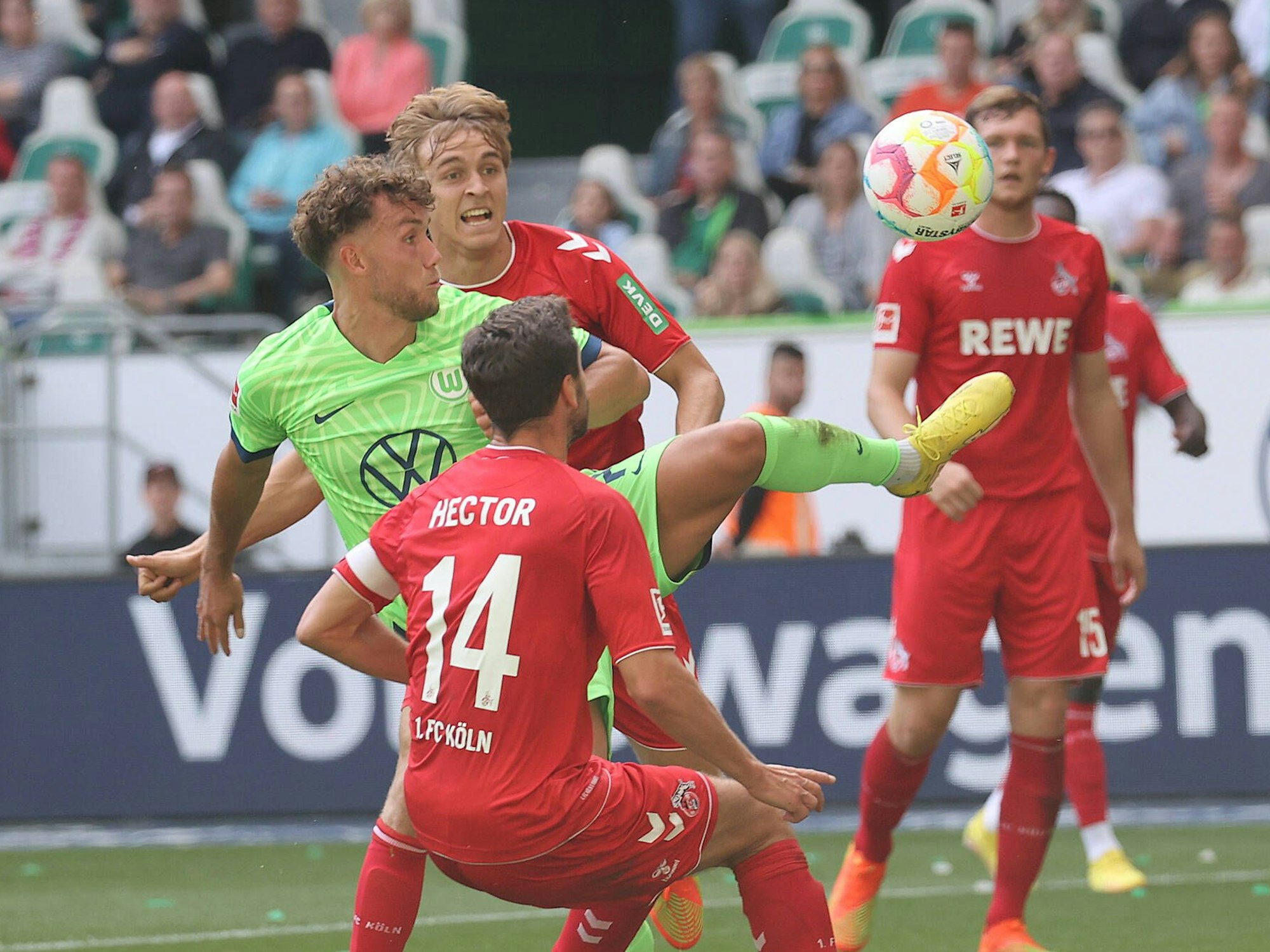 Kölns Jonas Hector im Zweikampf mit Wolfsburgs Luca Waldschmidt. Im Hintergrund versucht Kölns Timo Hübers ebenfalls an den Ball zu kommen.