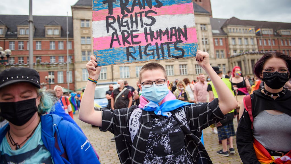 Eine Teilnehmerin hält im Rahmen des CSD in Kiel (Juni 2021) ein Schild mit der Aufschrift „Trans Rights are Human Rights“ (Trans-Rechte sind Menschenrechte) in die Höhe.