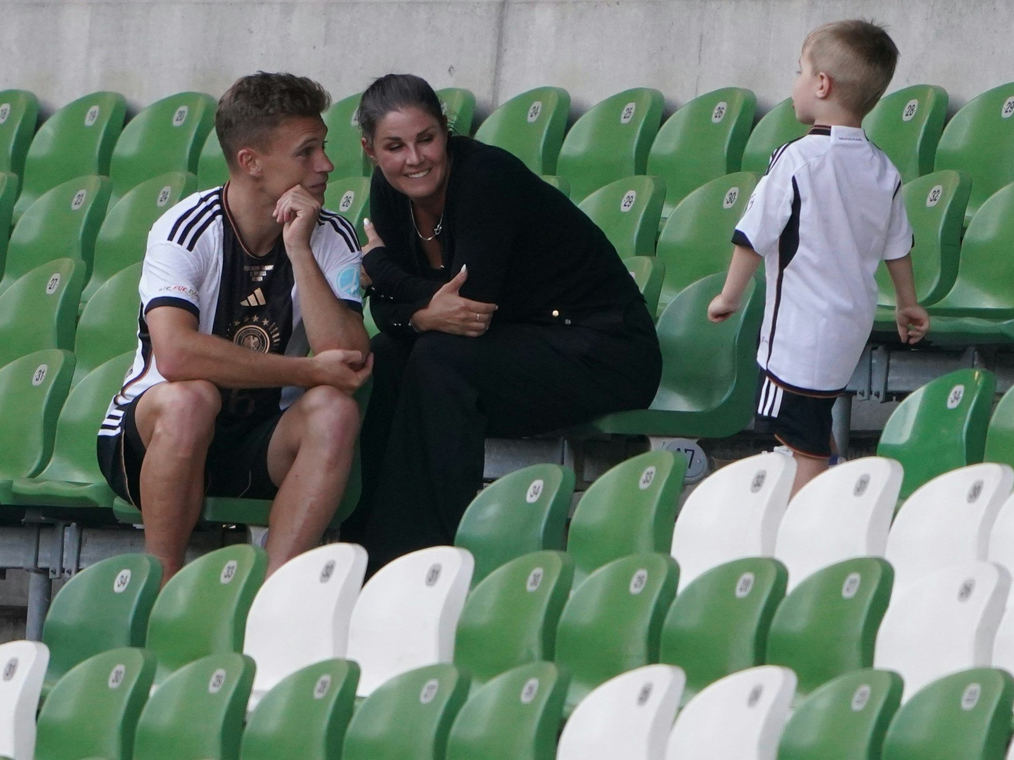 Deutschlands Joshua Kimmich sitzt mit seiner Frau Lina und Kind nach dem Spiel auf der leeren Tribüne.