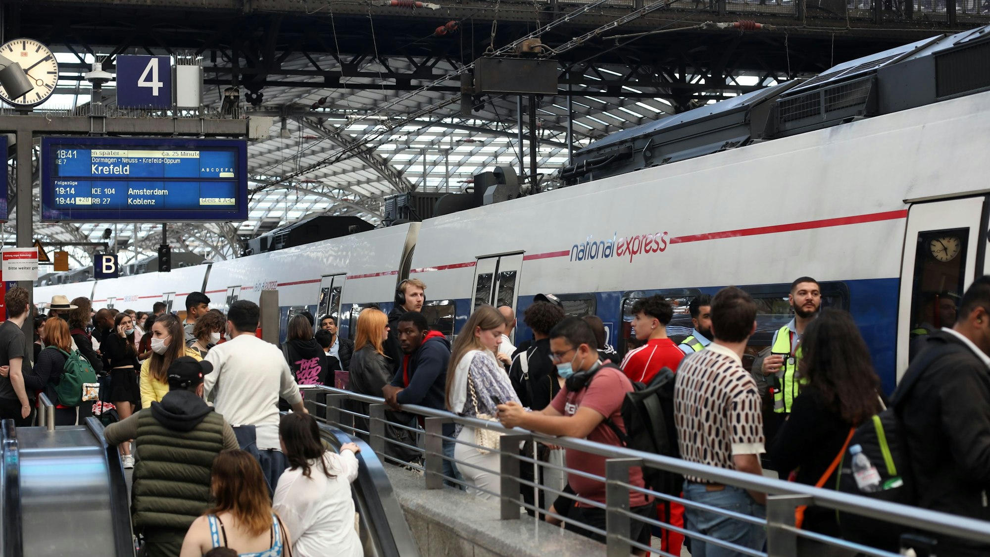 Ein ICE fährt am Kölner Hauptbahnhof ein, dutzende Menschen warten am Gleis.