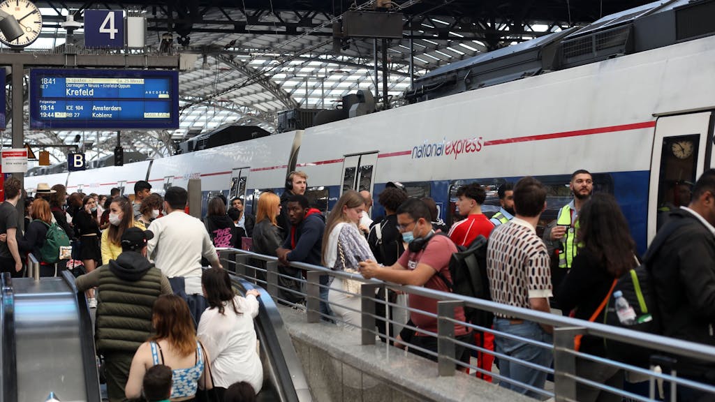 Ein ICE fährt am Kölner Hauptbahnhof ein, dutzende Menschen warten am Gleis.