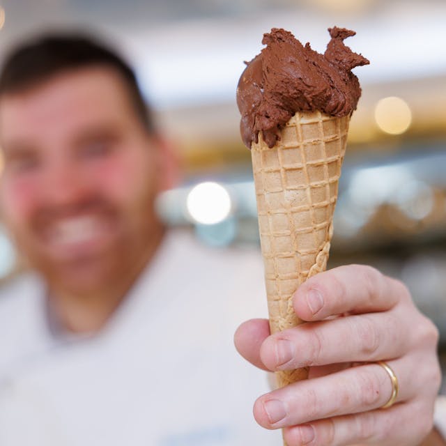 Der Eismacher Luca de Rocco hält in seinem Eiscafé eine Waffeltüte mit einer Kugel veganem Schokoladeneis in der Hand.&nbsp;