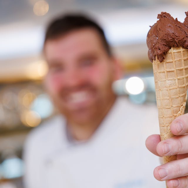 Der Eismacher Luca de Rocco hält in seinem Eiscafé eine Waffeltüte mit einer Kugel veganem Schokoladeneis in der Hand.&nbsp;
