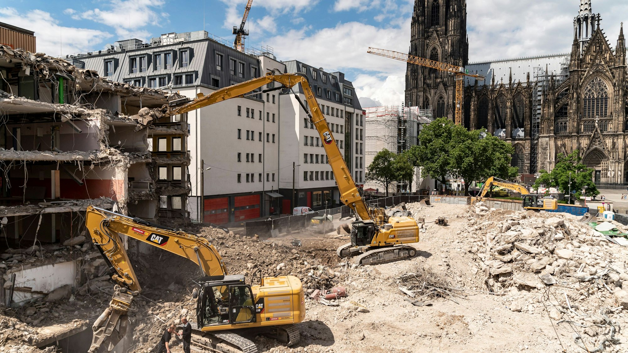 Das Bild zeigt Bagger, die ein Gebäude nahe des Kölner Doms abbrechen.