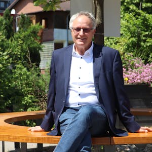 Bernhard Helfer sitzt auf einer der Bänke im neu gestalteten Außenbereich der Schule.