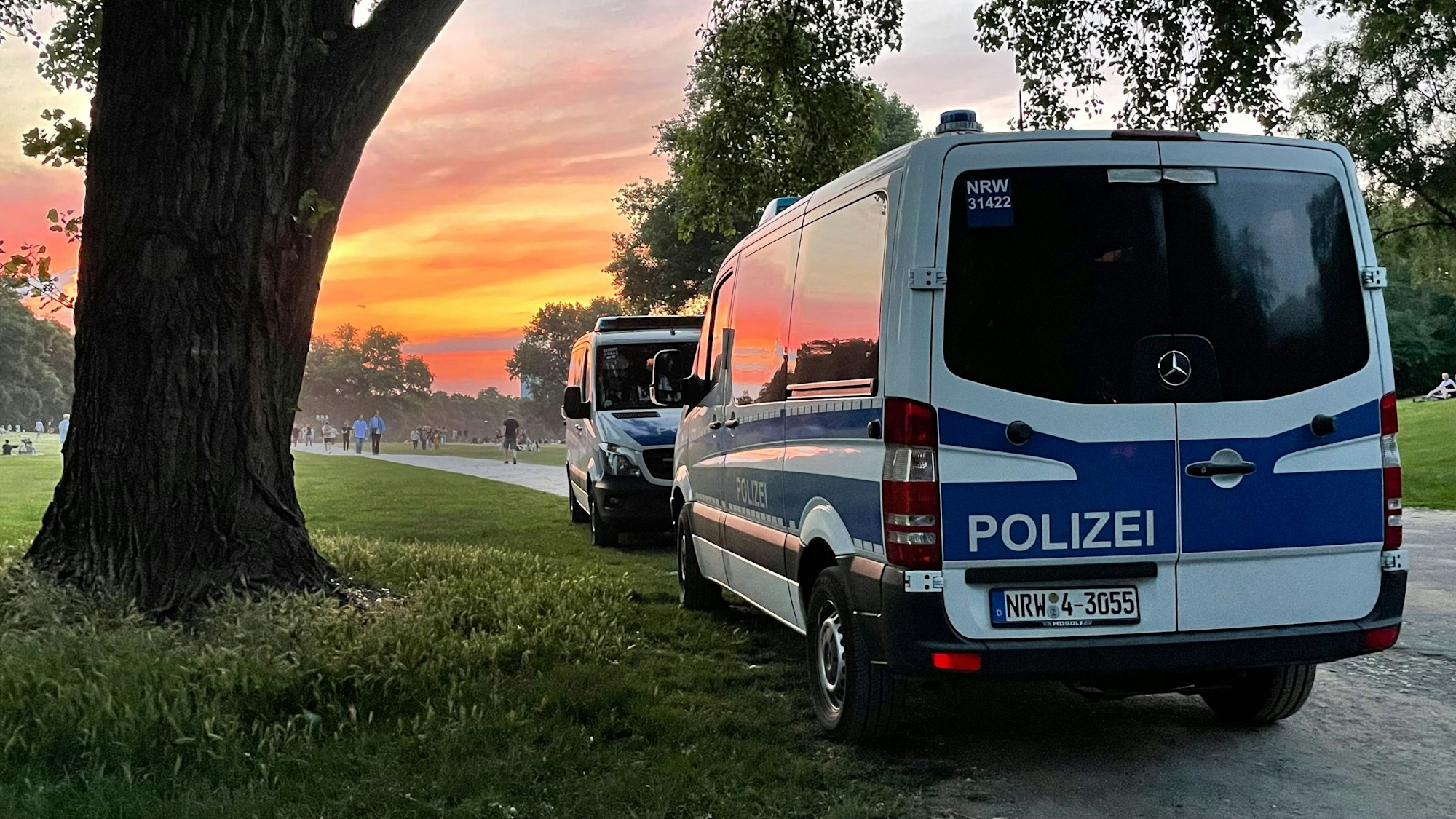 Polizei-Autos vor dem Sonnenuntergang am Aachener Weiher in Köln.