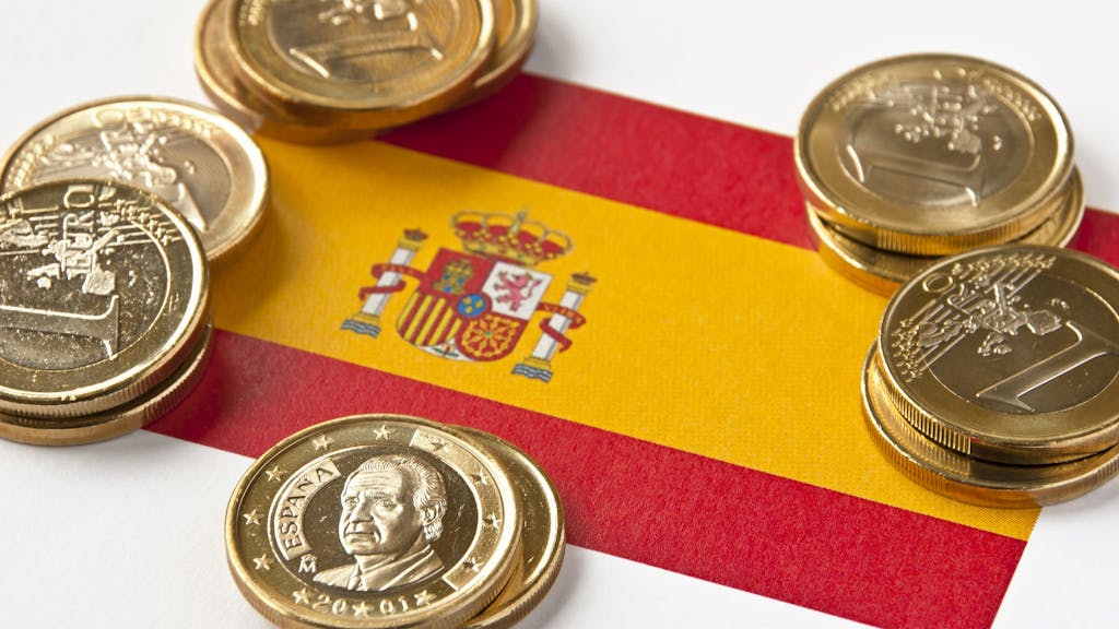 Münzgeld liegt auf einer Spanienflagge.