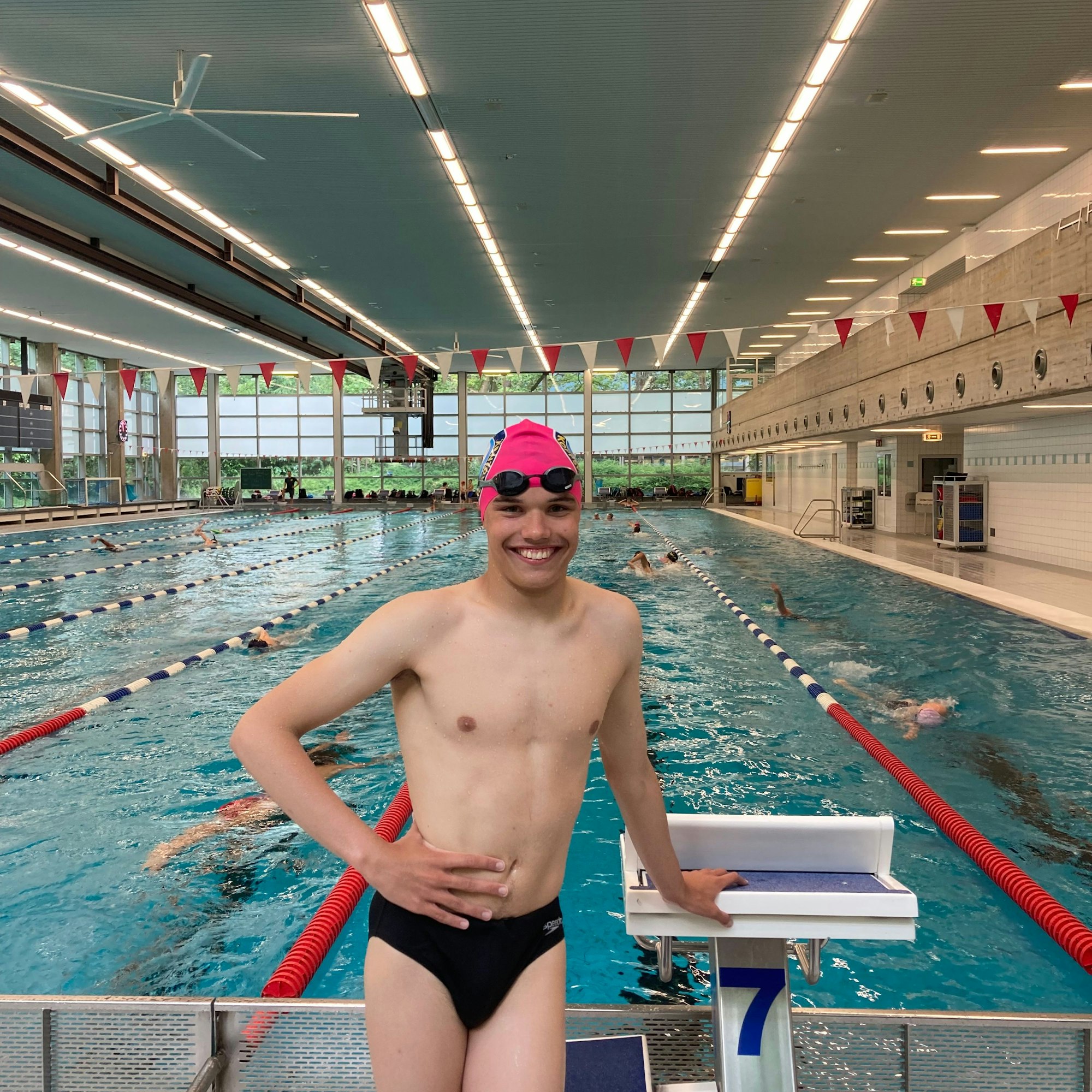 Porträt von Schwimmer Andriy vor dem Startblock, im Hintergrund das Becken