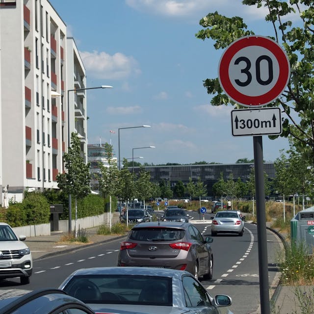 Straßenabschnitt mit einem Tempo 30 Schild, auf dem in beide Richtungen Autos unterwegs sind