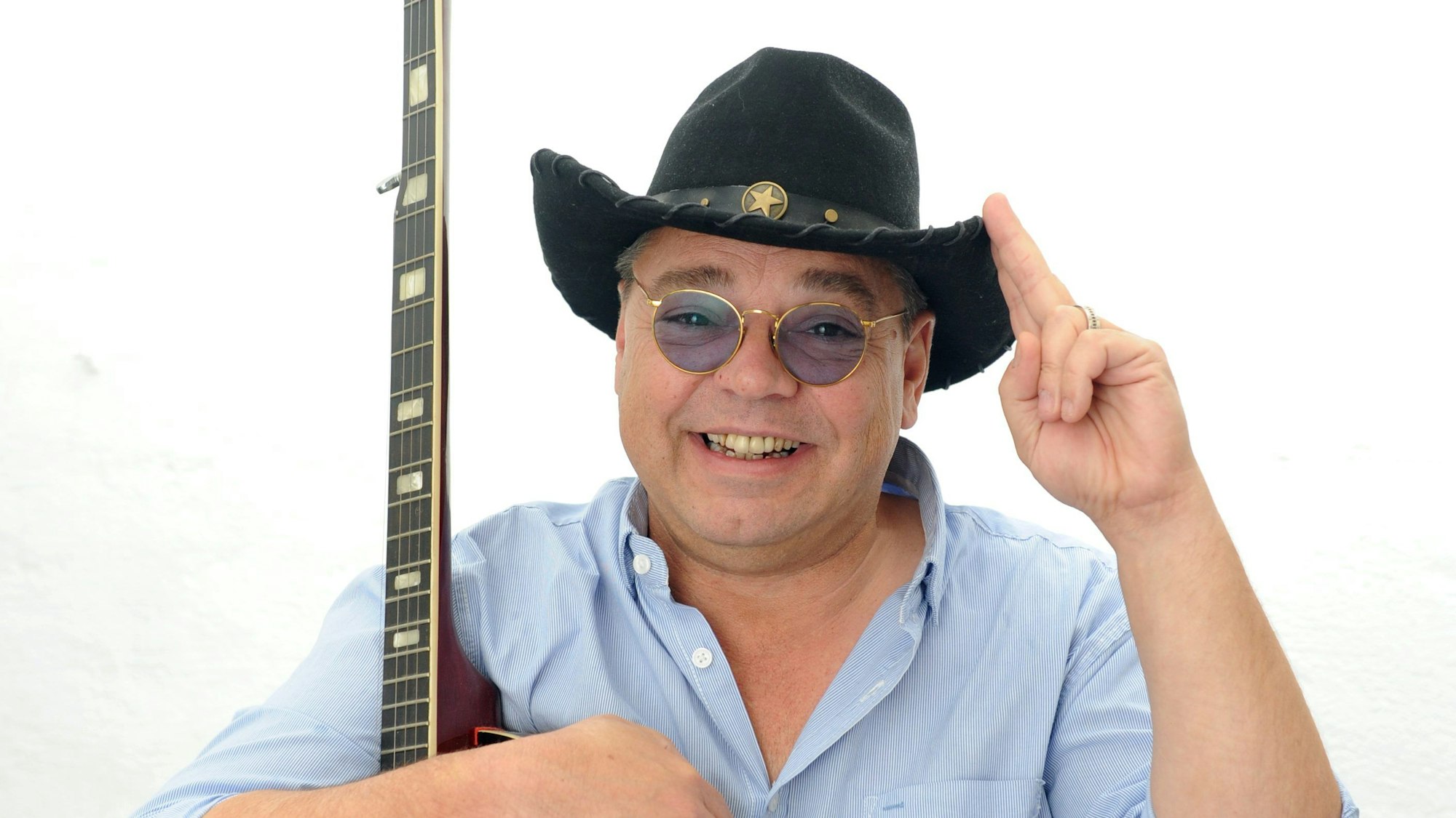 Micky Brühl mit Cowboyhut und Gitarre.