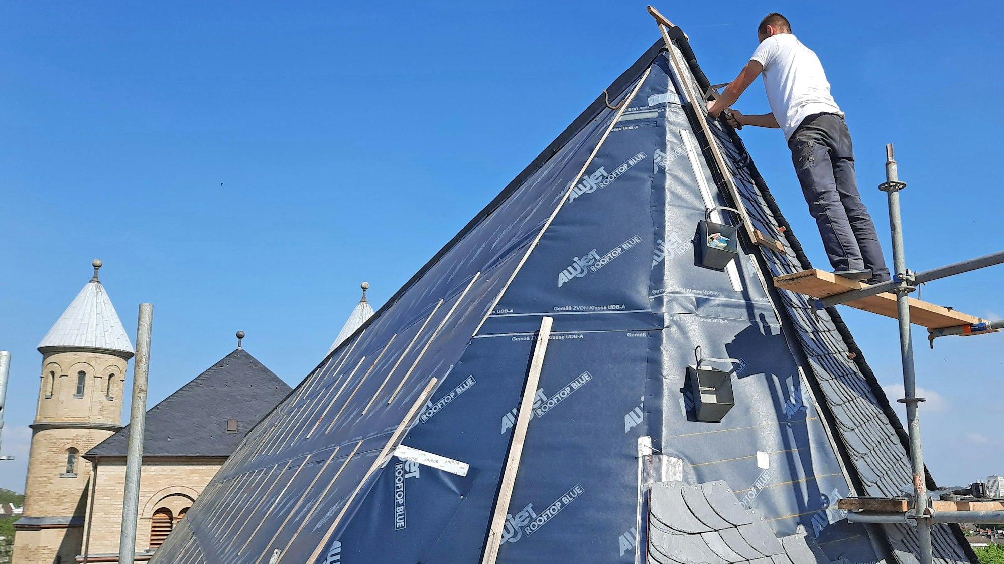 Ein Arbeiter deckt das Dach der Kirche bei gutem Wetter neu.