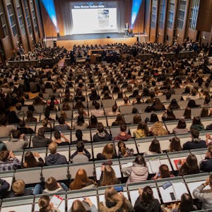 Studierende verfolgen im Hörsaal im Hauptgebäude der Universität zu Köln die Erstsemesterbegrüßung. Viele Studierende leben bei ihren Eltern.