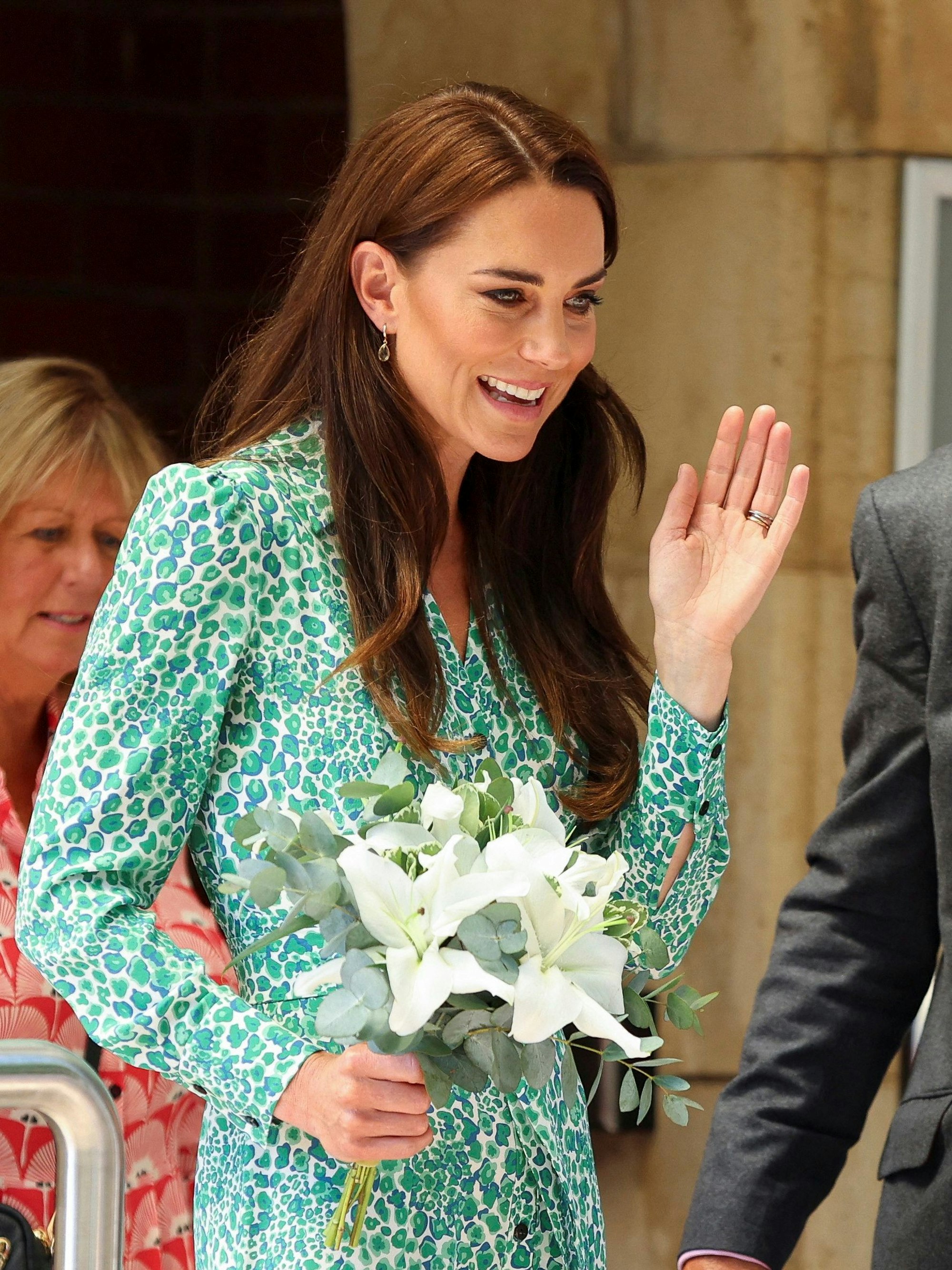 Prinzessin Kate hält Blumen und winkt Kindern zu. Diese sind nicht im Bild.