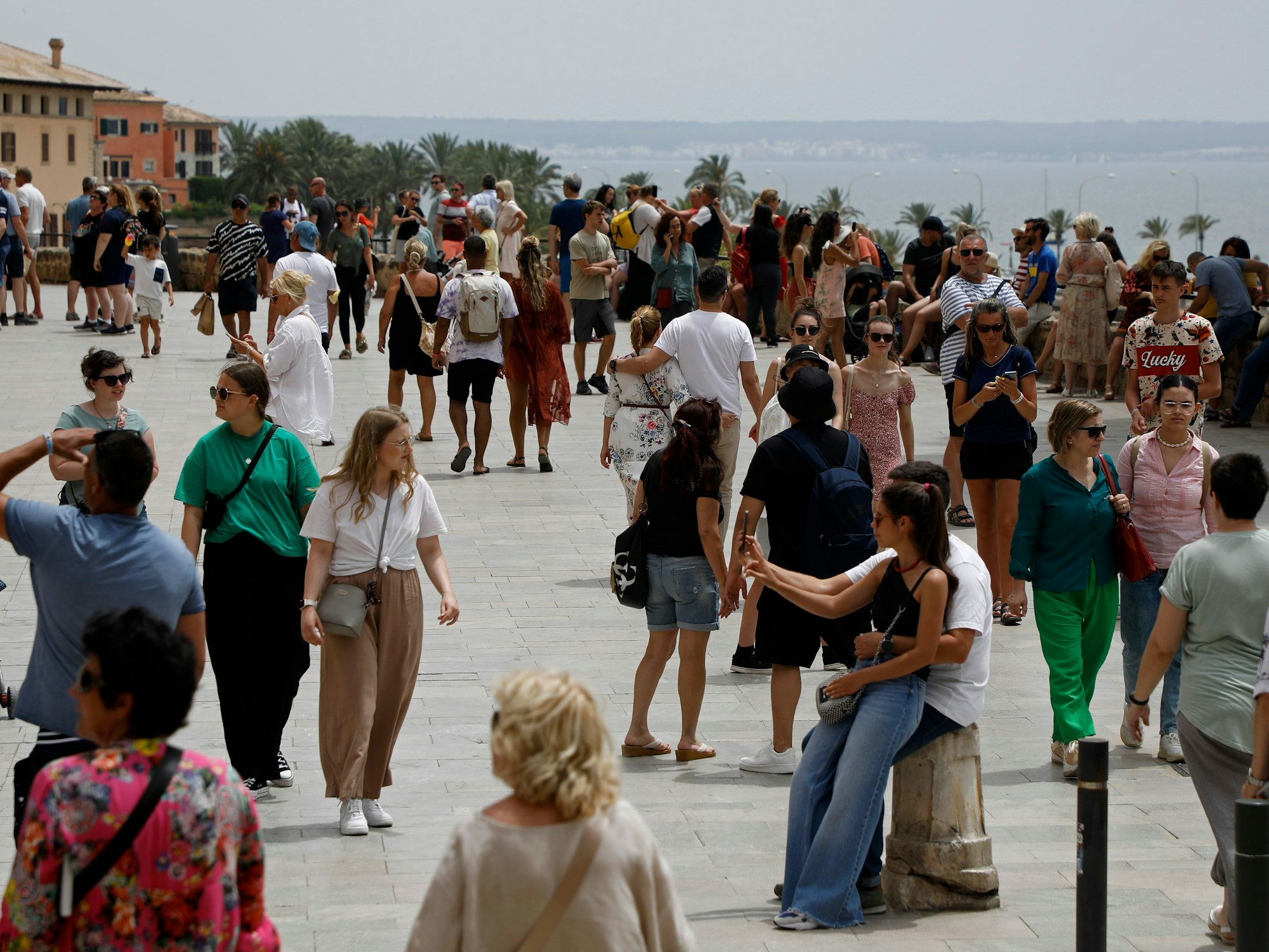 Touristen schlendern über eine Promenade in Palma de Mallorca.