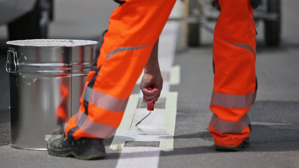 Ein Arbeiter vervollständigt eine Straßenmarkierung 