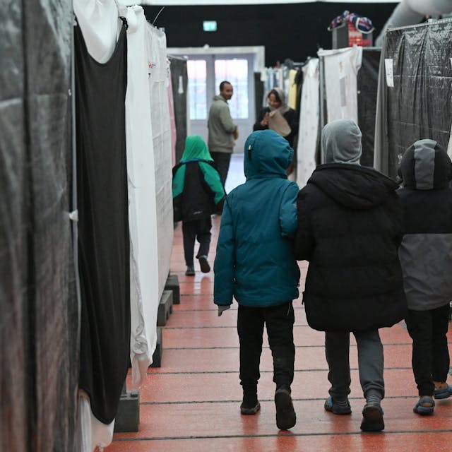 Drei Flüchtlingskinder gehen durch ein Zelt der Flüchtlingsunterkunft im hessischen Bensheim.
