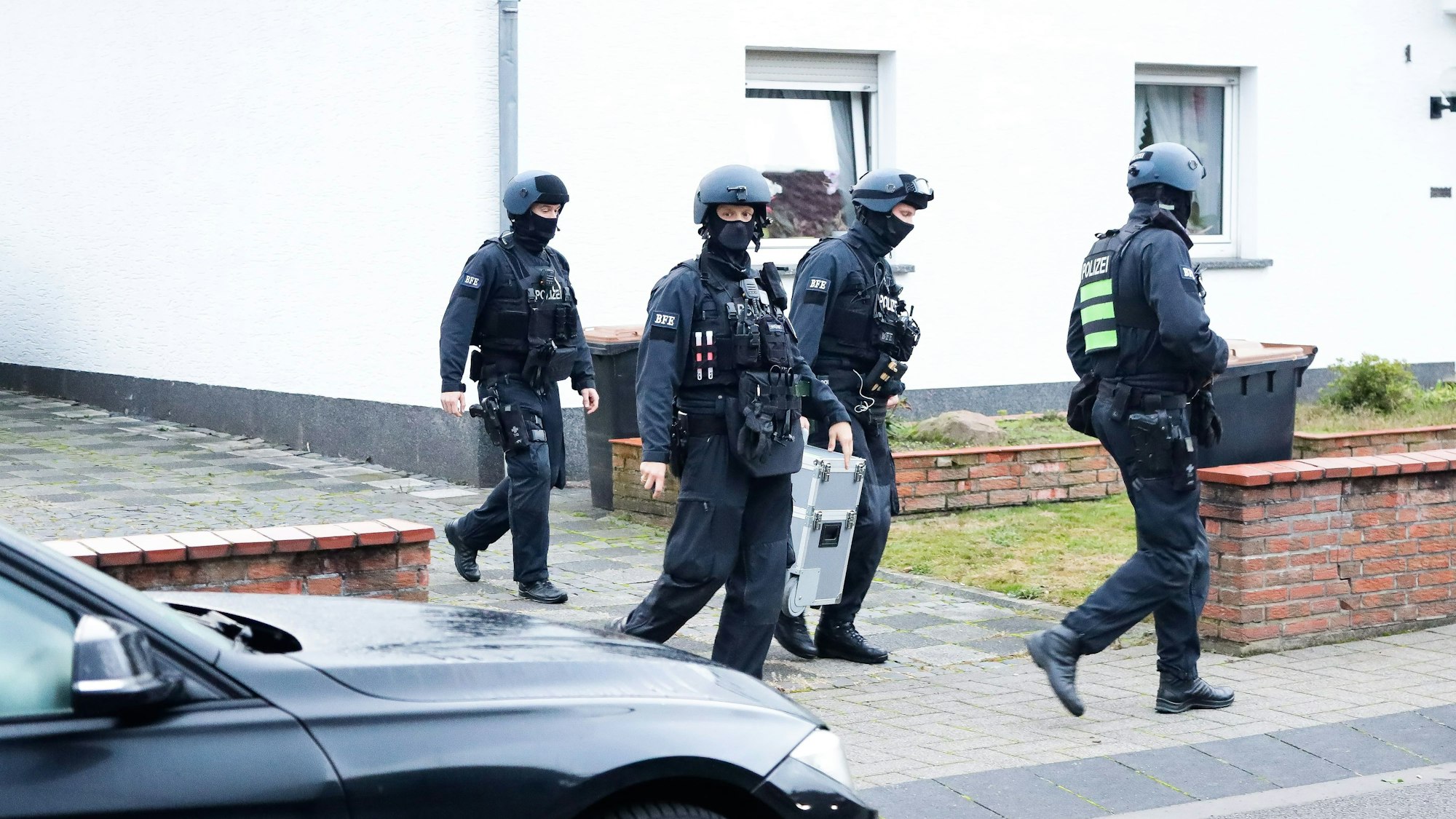 Einsatzkräfte der Polizei bei einer Razzia in einer Einfahrt in Köln.