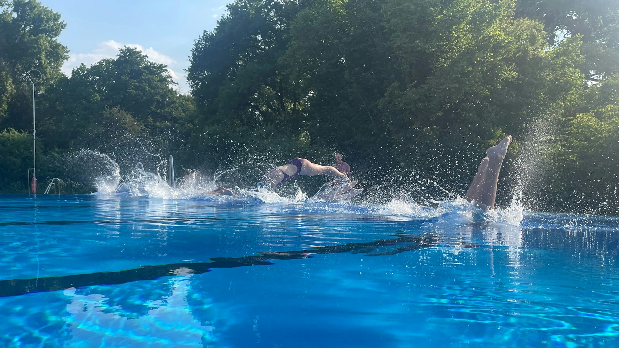 Schwimmer springen in ein Wasserbecken.